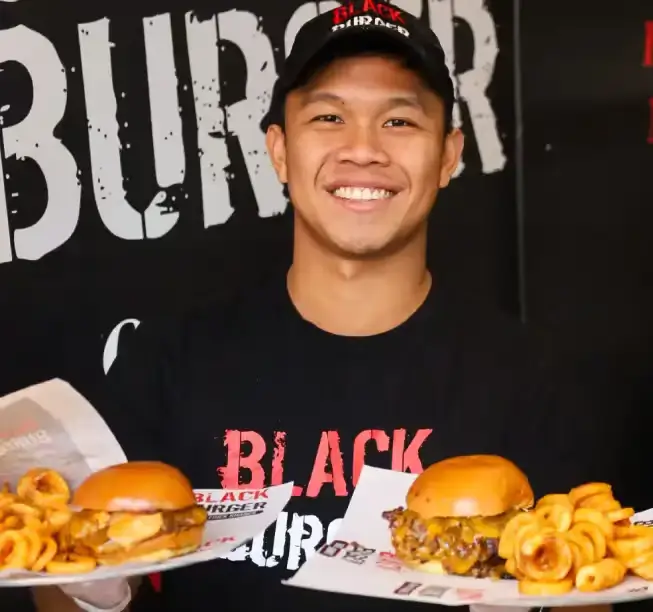 Waiter serving two double cheese burgers with curly fries at Black Burger restuarant at Canal Street, NYC